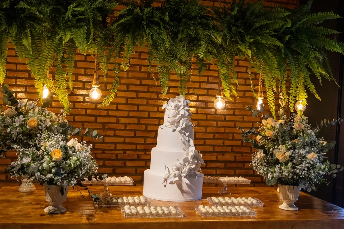 Mesa do bolo com samambaias e flores
